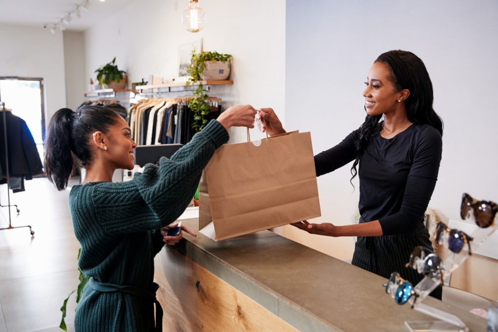 A cashier handing the paper bag to the customer