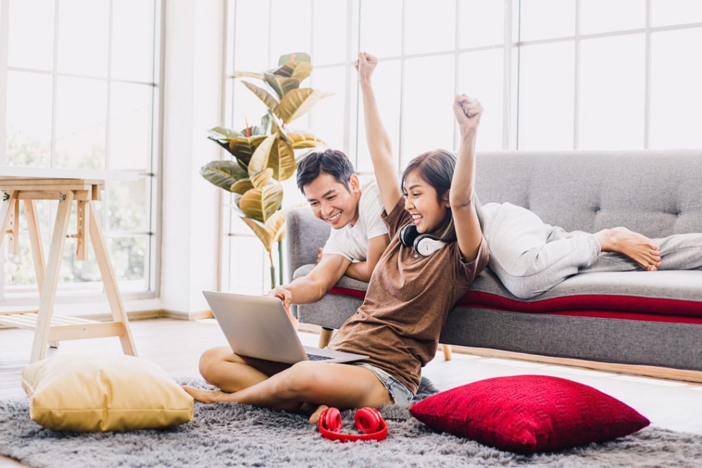 A joyful woman sitting on the floor with her laptop on her lap